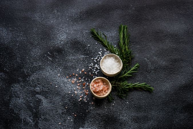 Top view of salt bowls and rosemary on kitchen counter