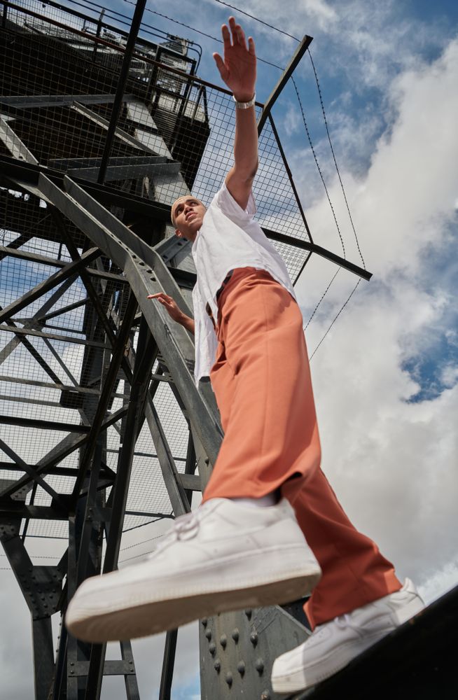 Stylish young man stepping off industrial structure