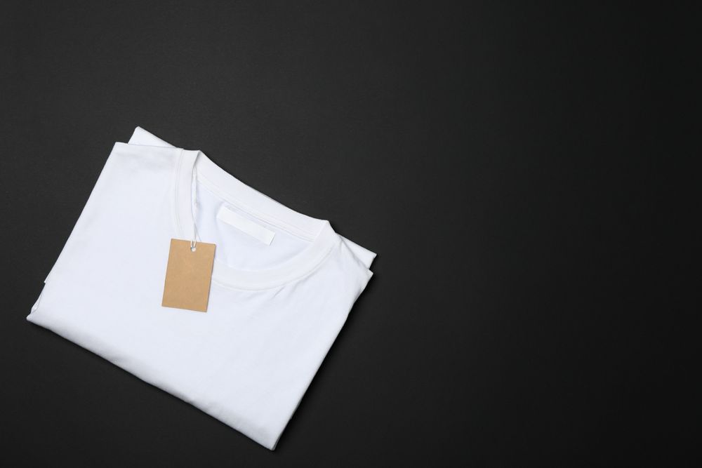 Folded blank plain t-shirt with tag on dark background, space for text