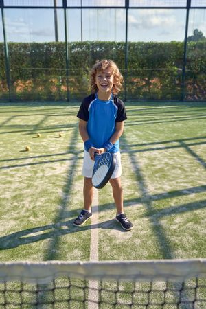 Cheerful boy with racket on playground