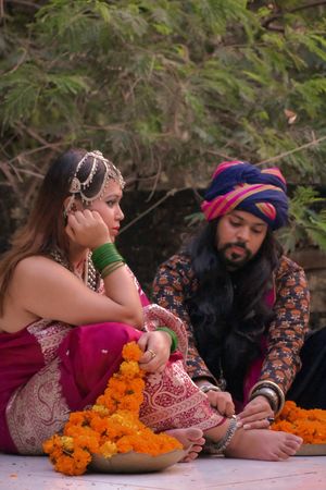 Indian man putting an anklet on woman's ankle sitting on ground