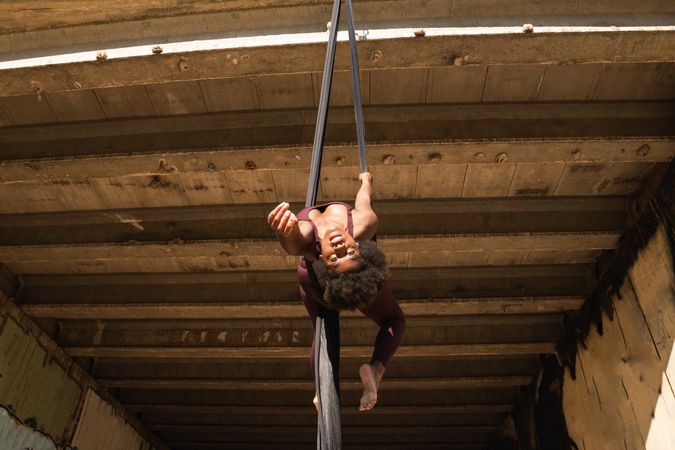 Fit woman doing yoga with aerial silks in city