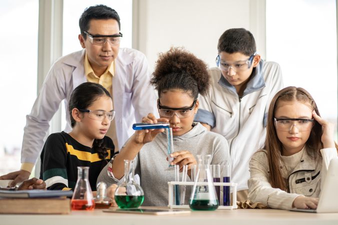 Multi-ethnic students with science teacher doing experiment