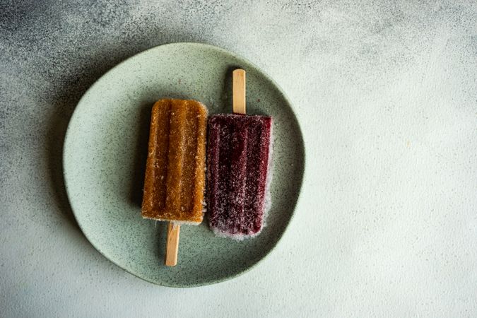 Two fruity ice cream pops on ceramic plate