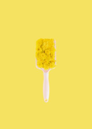 Centered hair brush with yellow spring flowers on bright yellow background