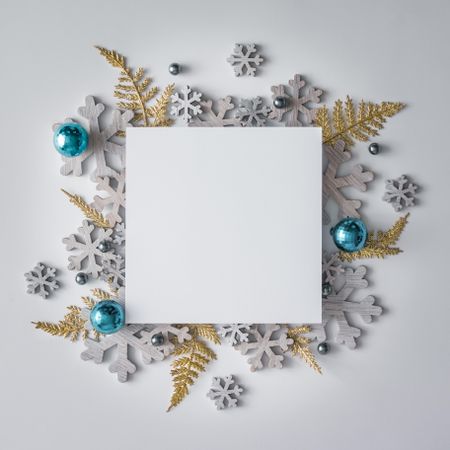 Festive winter decoration and snowflakes behind square paper card