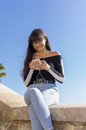 Portrait of a young woman texting while sitting outdoors