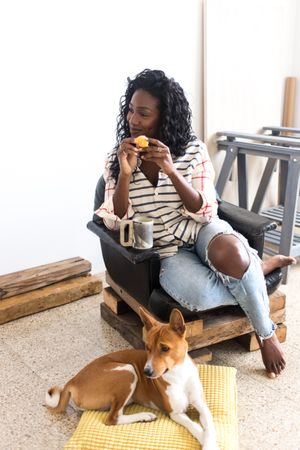 Calm woman eating orange with dog at her feet