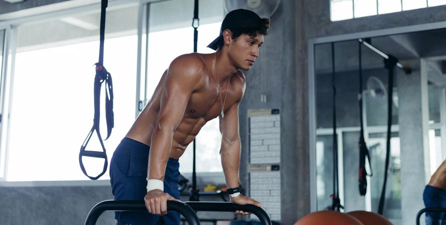 Male in cap working out his upper body in gym
