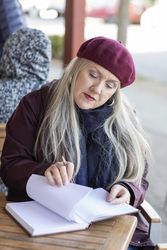 Woman writing notes in a notebook at patio cafe