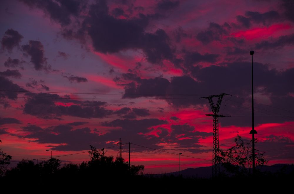 Utility poles against sunset sky