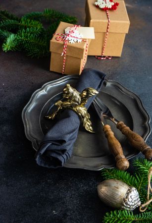 Dark plate with knife and fork on table with pine and gifts