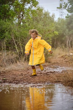 Little boy in raincoat running in countryside
