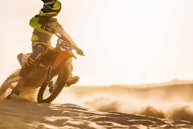 Motocross racer riding motorcycle in desert