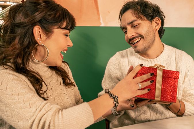 Happy couple celebrating, a man gives a surprise gift to his laughing girlfriend