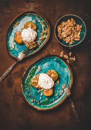 Roasted pumpkin and walnut dessert, with cream and syrup on ocean colored ceramic plates