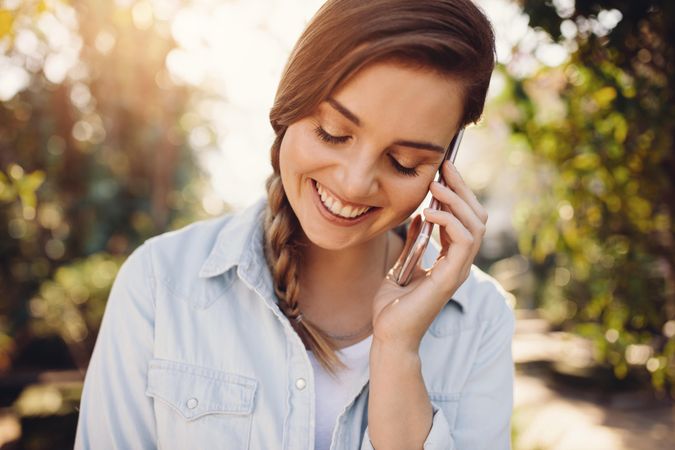Female talking on cell phone smiling and looking down outdoors