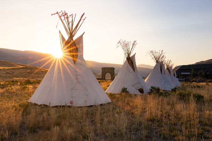 Montana, United States - August 17, 2022: Line of teepees in the mountains at dusk with sun flare
