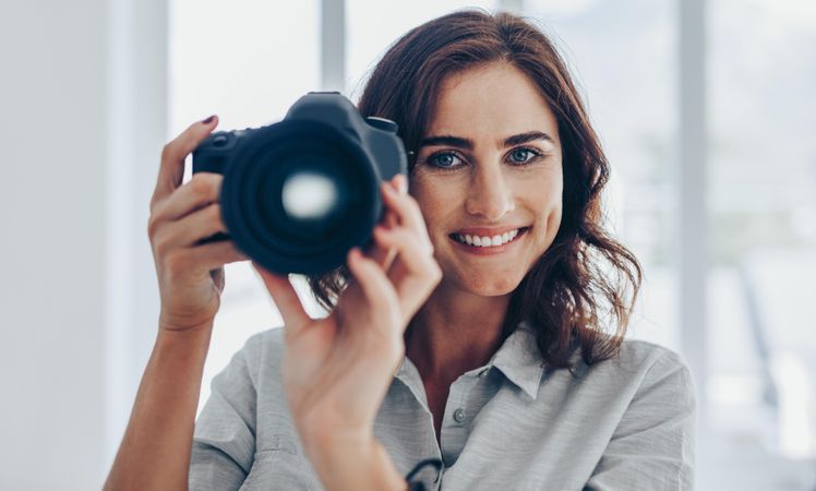 Portrait of happy photographer holding camera up with hands
