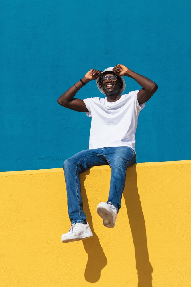 Happy man sitting on colorful wall