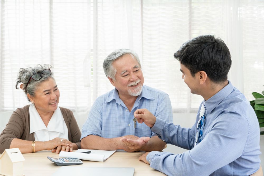 Happy mature Asian couple receiving key house from real estate agent