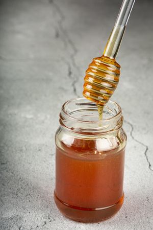 Honey in glass jar on the table.