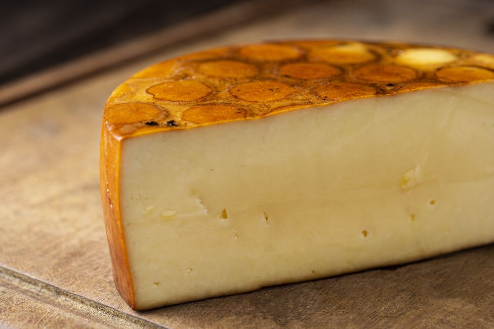 close up of cheese round half on bread board