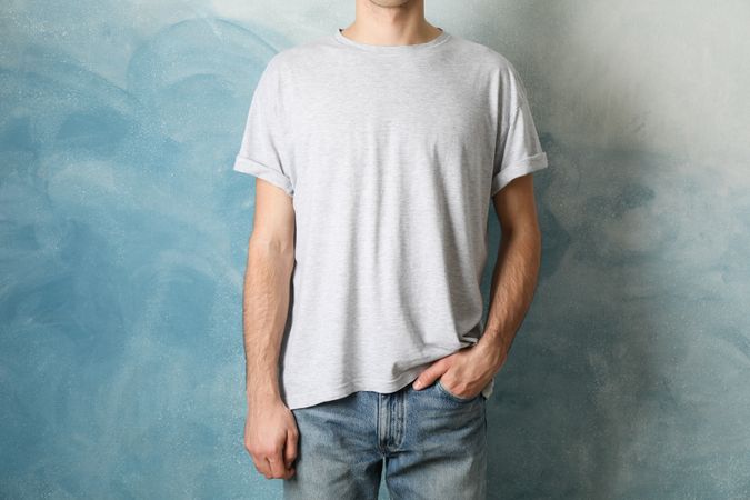 Men in blank grey t-shirt against blue background, space for text