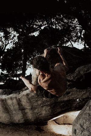 Man practicing rock climbing among large rocks in a forest