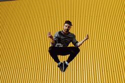 Man jumping near yellow wall