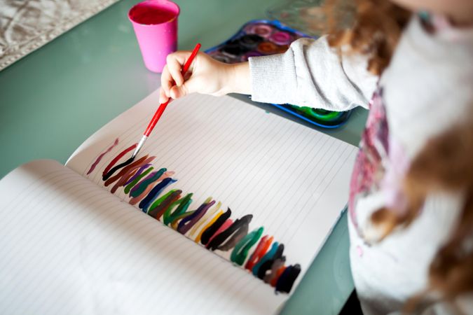 Cropped image of child painting on a notebook using water colors