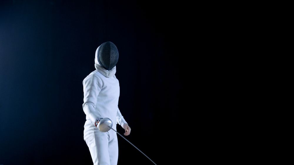 Fully Equipped Skilled Fencer Training with a Foil. He Practices Attack, defense,  Leap, Thrust and Lunge.