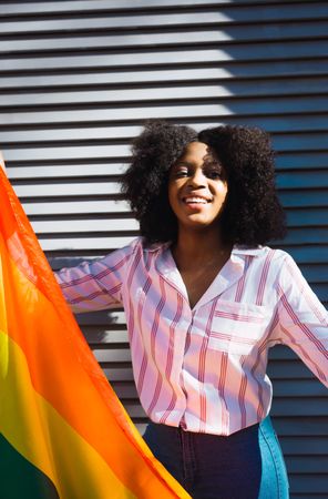Happy Black woman posing happily with the LGBT flag
