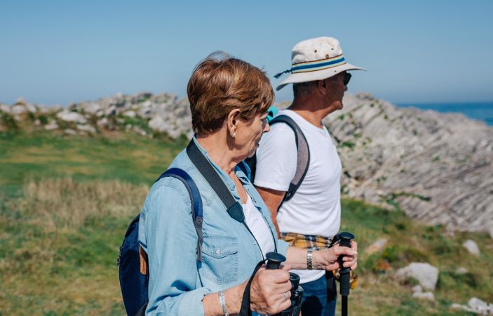 Mature man and woman with poles hiking outdoors