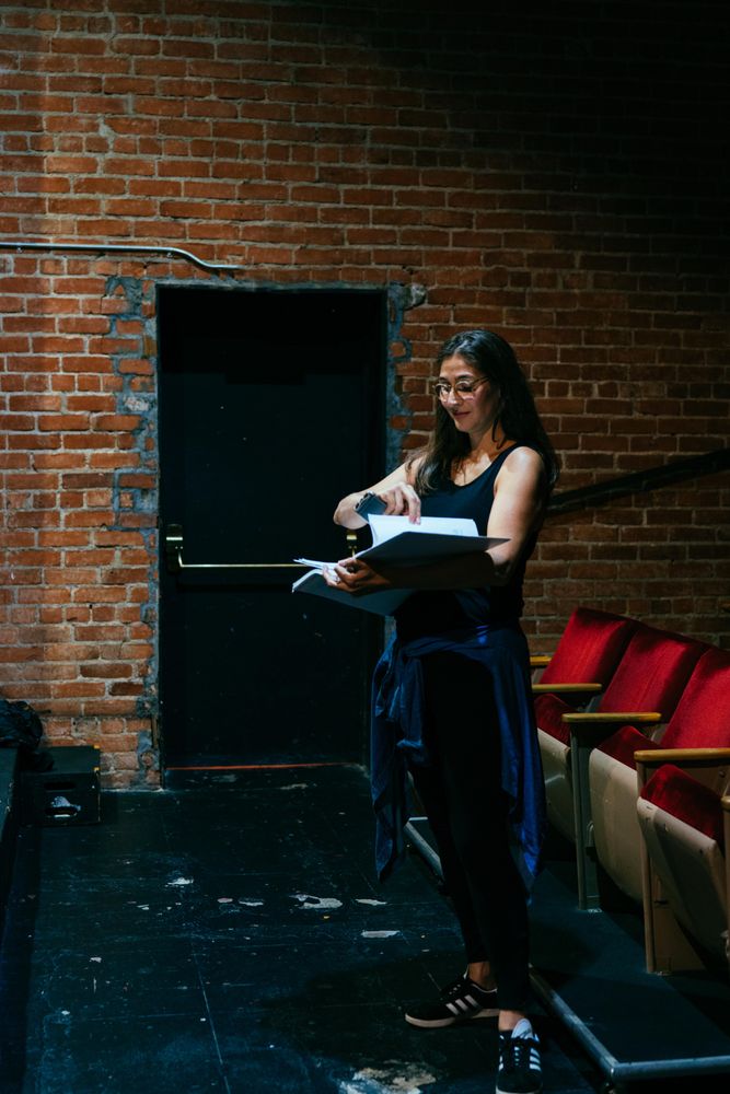 Female director standing with script in the front of the theater