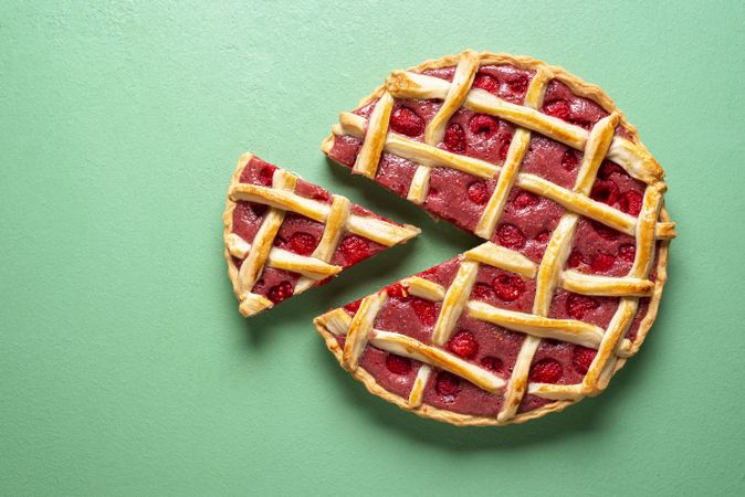 Sliced raspberry tart top view on a green background