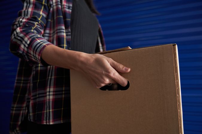 Unrecognizable woman carrying cardboard box