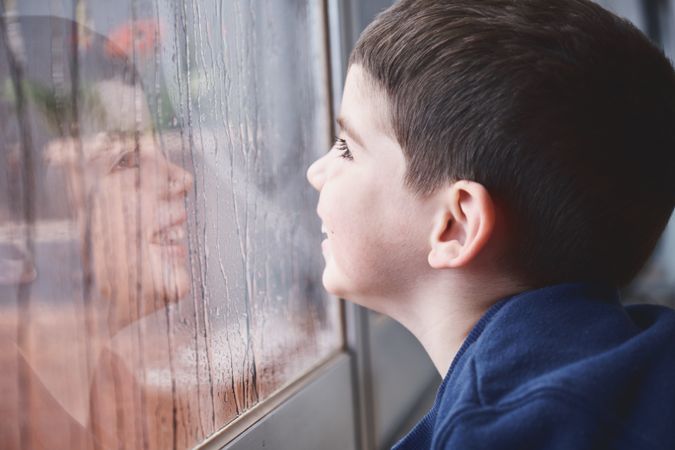 Boy breathing on wet glass