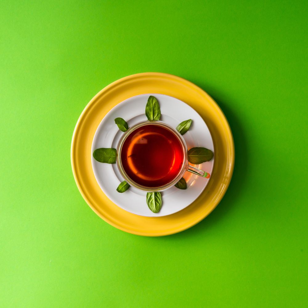 Tea in glass cup with leaves  on green background
