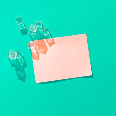 Ice cubes and pink paper card note on vivid blue background