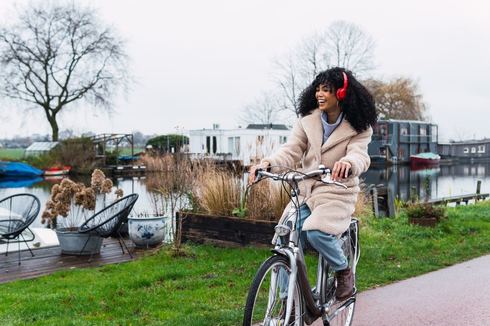 Excited Black woman in headphones riding bicycle
