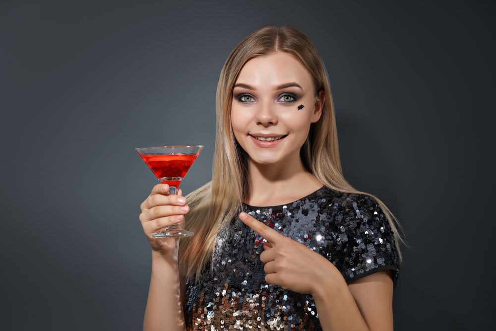 A woman at a party in the style of Halloween with a cocktail in her hands