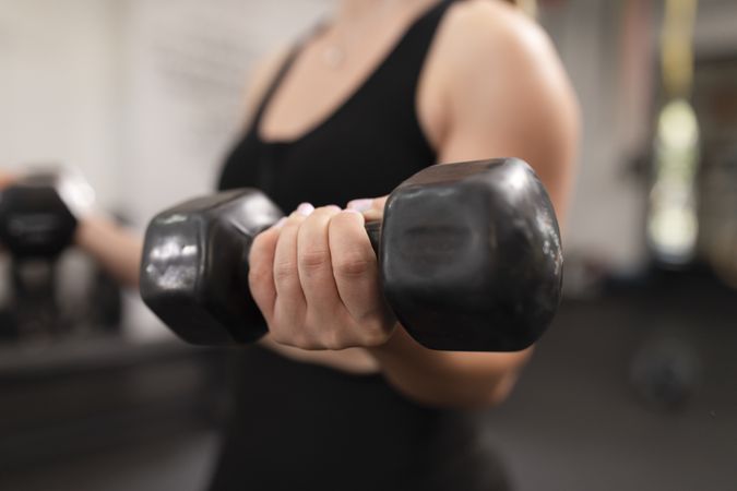 Close up of a female weightlifter holding a dumbbell in her hand
