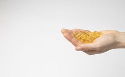 The hand of a woman holds a handful of oil capsules with omega 3, food supplement