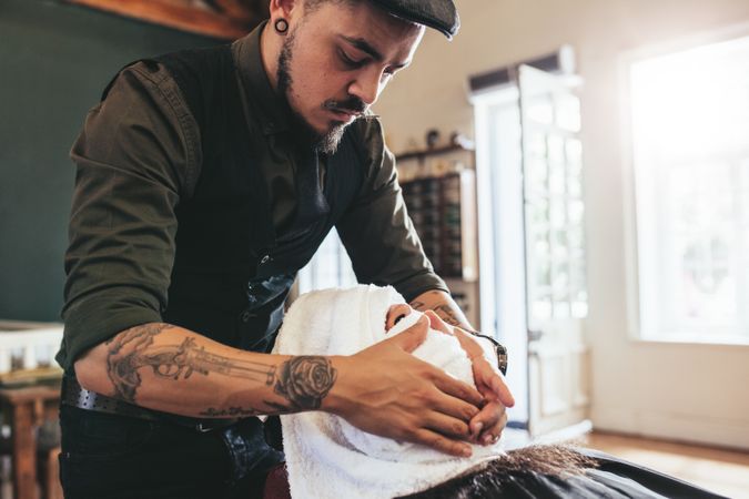 Barber applying warm towel over customers face