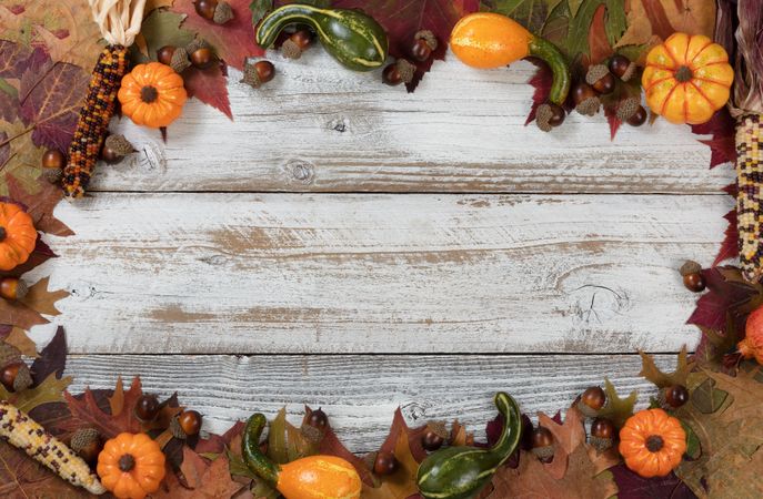 Complete circle border of Autumn foliage with other fall decorations on rustic wood