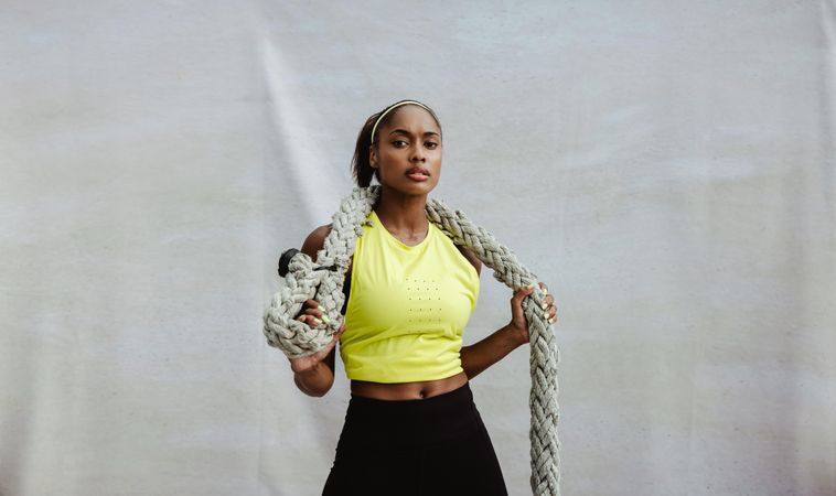 Confident athlete woman holding battling rope