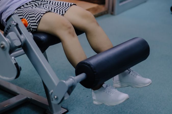 close up of a woman's legs using a leg extension machine, sitting on a cushioned chair