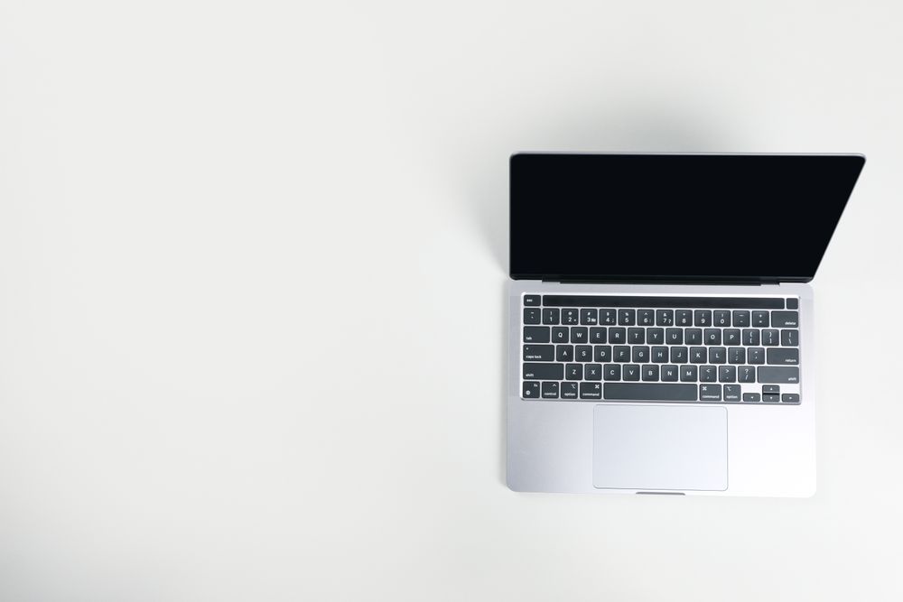 Top view of opened silver laptop and keyboard on desk with copy space