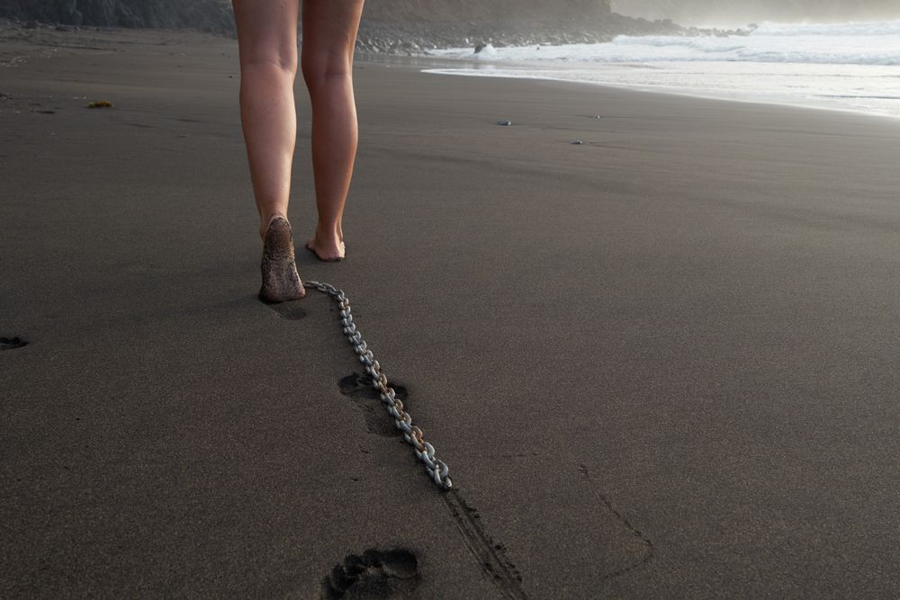 Crop woman walking on sand with chain braking